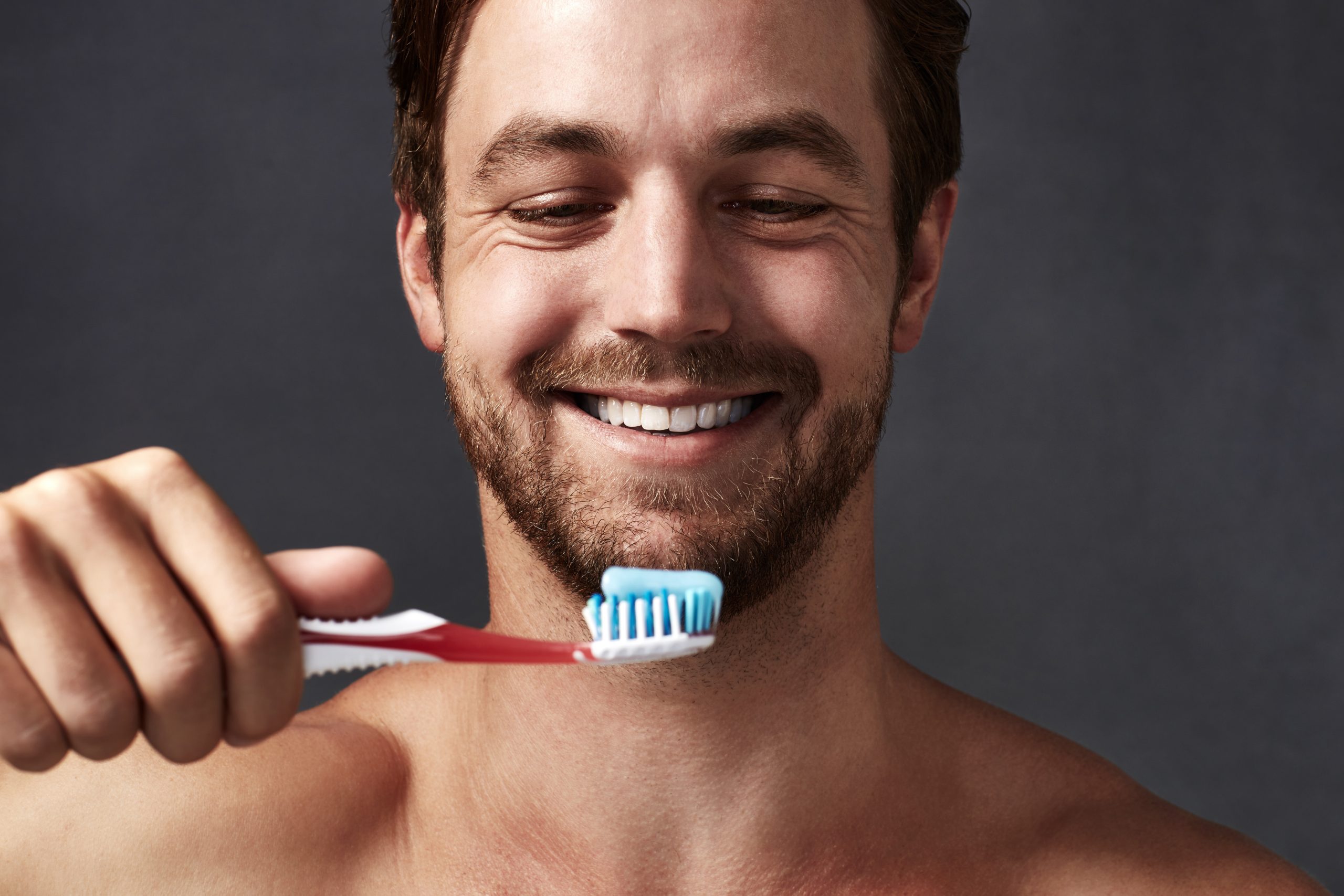 Keeping those pearly whites shining and healthy. a handsome young man brushing his teeth against a grey background