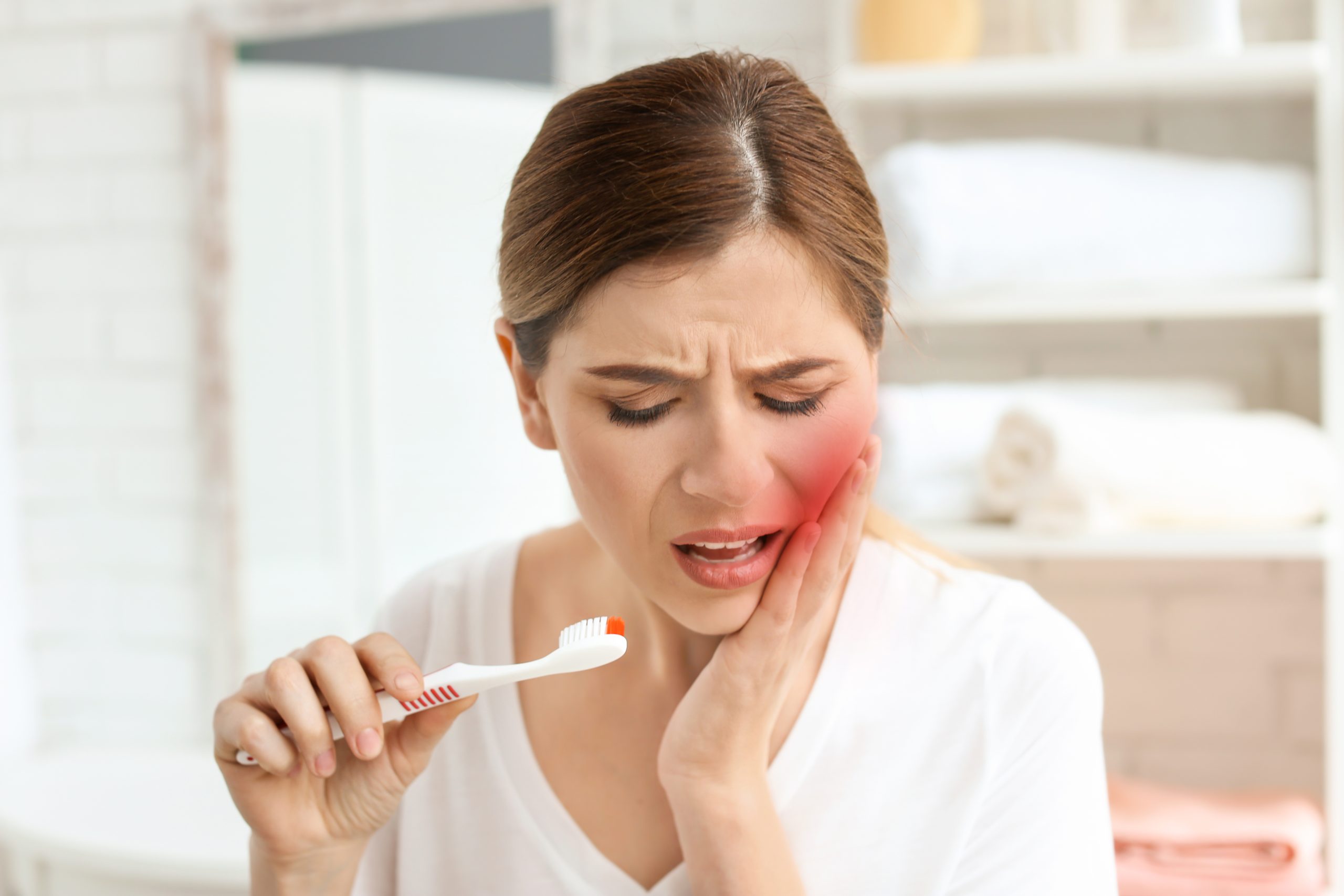 Young woman suffering from acute toothache indoors