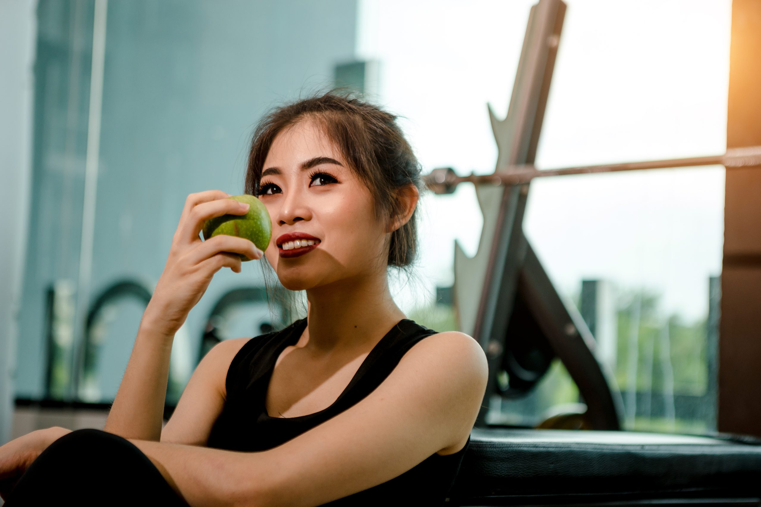 Asian woman exercising in the gym, Young woman workout in fitness for her healthy and office girl lifestyle. She is holding green apple.